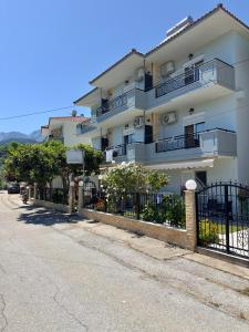 a large white building with balconies and a fence at Golden View Studios in Chrysi Ammoudia
