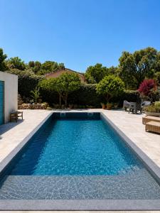 a swimming pool with blue water in a yard at LOGEMENTS ACCÈS PISCINE - T2 Résidence Serena in Cuttoli-Corticchiato