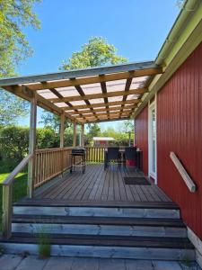a deck with a pergola on a red house at Sonjas Camping & Stugor in Löttorp