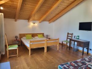a bedroom with a bed and a desk and a television at B&B Le Colombine in Abbadia Lariana