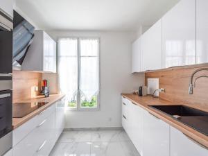 a white kitchen with a sink and a window at Cour Royale Disneyland Paris in Chessy