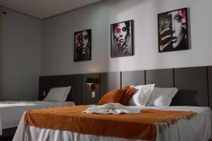 a hotel room with two beds and pictures on the wall at Pousada Villa Ricca Park in Niquelândia +31 photos
