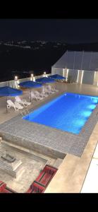 a large swimming pool with chairs and umbrellas at night at Green Vista in Māḩiş