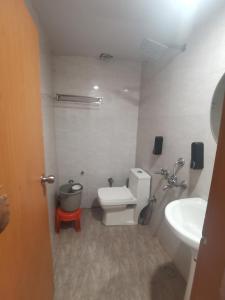 a small bathroom with a toilet and a sink at Tira Hotel and Cafe in Rudraprayāg +3 photos