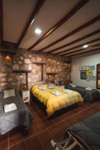 a bedroom with two beds and a stone wall at La Llama Negra in Tilcara