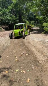 Ein grüner Jeep fährt eine unbefestigte Straße entlang. in der Unterkunft Frailin Merete in San Felipe de Puerto Plata