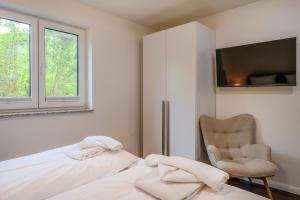 a bedroom with a bed and a chair and a window at Dünenquartier Apartment 24 in Zingst