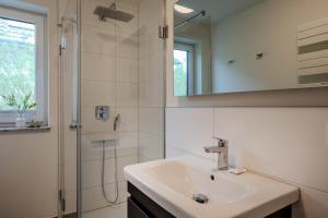 a white bathroom with a sink and a shower at Dünenquartier Apartment 24 in Zingst +17 photos