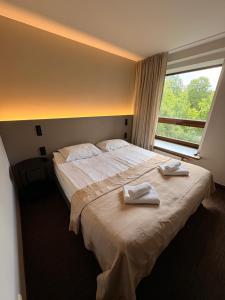 a bedroom with a large bed with two towels on it at Delita Cozy Hotel in Druskininkai +45 photos