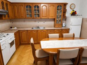 a kitchen with wooden cabinets and a table with chairs at Apartman Martina in Gospić