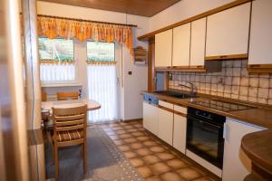 a kitchen with white cabinets and a table and chairs at Ferienwohnung Felsenidyll in Bundenthal