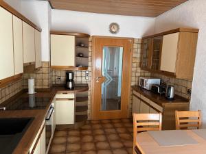 a kitchen with wooden cabinets and a table and a door at Ferienwohnung Felsenidyll in Bundenthal +11 photos
