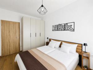a bedroom with a large white bed with a wooden headboard at Small Garden Apartman in Sárvár