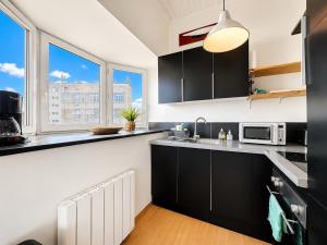 a kitchen with black cabinets and a microwave at Villaloha - Appartement avec terrasse in Bray-Dunes