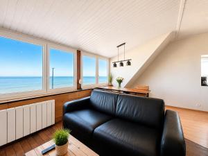 a black leather couch in a living room with windows at Villaloha - Appartement avec terrasse in Bray-Dunes
