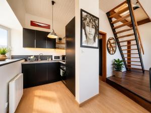 a kitchen with black and white cabinets and a staircase at Villaloha - Appartement avec terrasse in Bray-Dunes