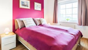 a bedroom with a bed with a pink wall at Haus an der Pferdekoppel Nr 3 in Fehmarn