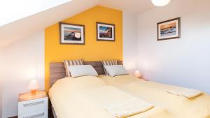 a bedroom with a large bed with yellow walls at Haus an der Pferdekoppel Nr 2 in Fehmarn +2 photos