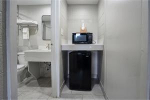 a bathroom with a sink and a microwave on a counter at Carolina Inn Anderson Clemson Area in Anderson