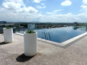 two white pots sitting on the edge of a roof at Kuching Kozi Square 2paxs Large Window CityView Infinity Pool 2E in Kuching +8 photos