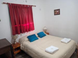 a bedroom with a bed with two blue pillows at Casa El Gavión in Villa Unión