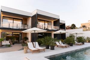 a house with chairs and umbrellas next to a swimming pool at Luxury Experience Suites in Toledo