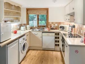 a kitchen with white appliances and a wooden floor at The Old Sawmill One - Uk49336 in Plumpton Green