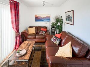 a living room with a leather couch and a coffee table at Beach Cottage in Gairloch