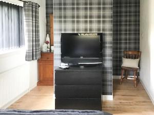 a living room with a television on a black dresser at Beach Cottage in Gairloch +6 photos