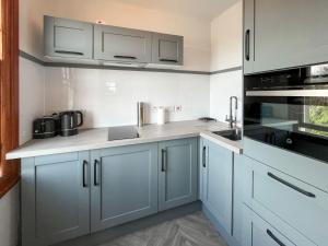 a kitchen with blue cabinets and white appliances at Avocet Apartment - Uk51130 in Carradale