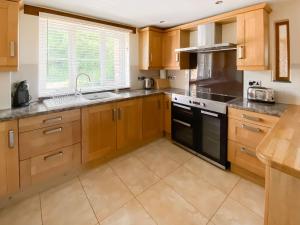 a kitchen with wooden cabinets and a black appliance at Cart-Tws Bach - Om8 in Treffynnon  +17 photos