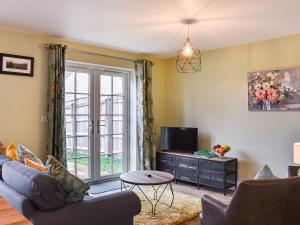 a living room with a couch and a tv at The Garth in Helmsley