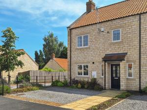 a brick house with a black door and a fence at The Garth in Helmsley