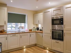 a kitchen with white cabinets and a window at The Garth in Helmsley +9 photos