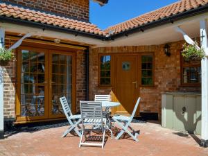 a patio with three chairs and a table in front of a house at Boothby Cottage in Willoughby