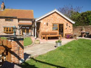 a brick house with a wooden bench in a yard at Boothby Cottage in Willoughby +10 photos