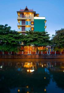 een gebouw met een reflectie in het water 's nachts bij Lamphu Tree House Boutique Hotel in Bangkok