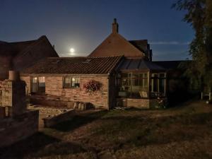 a house at night with the moon behind it at Elm Barn View in Freethorpe