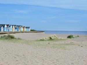 a row of houses on a beach next to the ocean at Plum Cottage in Anderby