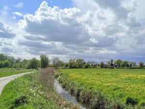 a dirt road through a field with a cloudy sky at Elm Barn Lodge in Freethorpe +7 photos
