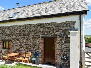 a brick house with chairs and a table and a grill at Cider Cottage - Uk11861 in North Tamerton