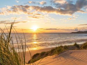 a sunset on a beach with the ocean at Lodge 33 in Woolacombe