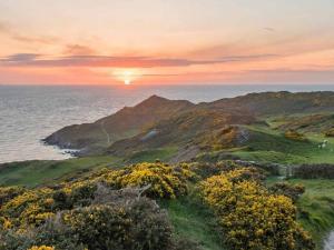 a view of the ocean with the sun setting on a mountain at Lodge 33 in Woolacombe +11 photos