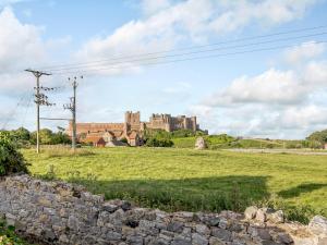a castle in the distance with a stone wall in the foreground at White Stag Cottage in Bamburgh