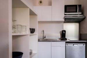 a white kitchen with a microwave and a sink at Le 82 - Studio pour 4 à 3 minutes de Disneyland Paris in Montévrain +10 photos