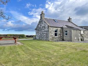 an old stone house with a bench in front of it at Broughton in Newton Stewart