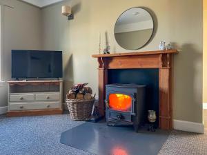 a living room with a wood stove and a mirror at Broughton in Newton Stewart