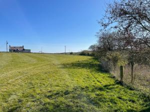 a grassy field with a house in the distance at Broughton in Newton Stewart