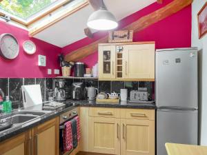 a kitchen with pink walls and a white refrigerator at Silk Hill Stables in Whaley Bridge