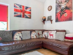 a brown leather couch in a living room with pillows at Silk Hill Stables in Whaley Bridge